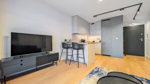 A modern kitchen with a central island, a dining area with bar stools, and a large flat-screen TV. - 6th Floor Studio with the River View (Wrocław)