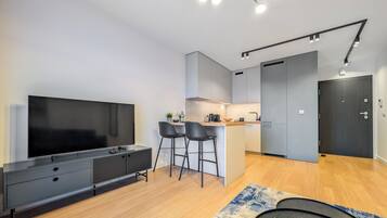 Una cocina moderna con una isla central, un comedor con taburetes de bar y un televisor de pantalla plana grande.