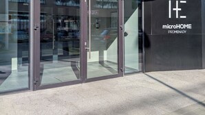 A modern building entrance with glass doors and a sign for 'microHOME PROMENADY'. - MicroHome Promenady Two-Level Apartment (Wroclaw)