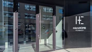 En moderne bygningseingang med glasdøre og et skilt med 'microHOME PROMENADY'.
