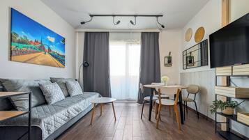 Et moderne opholdsrum med sofa, spisebord, stole og et fjernsyn.