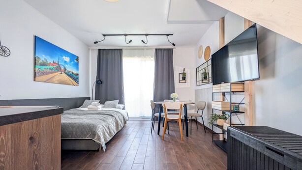 A modern bedroom with a bed, a desk, and a TV. - MicroHome Promenady Two-Level Apartment (Wroclaw)