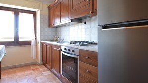 A kitchen with wooden cabinets, a gas stove, an oven, and a stainless steel refrigerator. - Amazing apartment in Suni with WiFi (Suni)