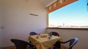 A small dining area with a table set for two, a window with a view of buildings, and a power outlet on the wall. - Amazing apartment in Suni with WiFi (Suni)