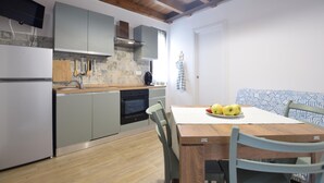 A compact kitchen with grey cabinets, a wooden countertop, and a dining table with chairs. There is a plate of fruit on the table. - Pet friendly apartment (Santo Stefano Di Magra)