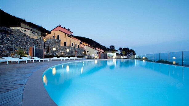 A swimming pool with lounge chairs and a stone wall. - Awesome home in Magliolo with sauna (Magliolo)