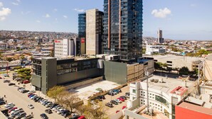 A high-rise hotel with multiple floors, a parking lot, and a view of the cityscape. - Modern Studio in Zona Rio with Panoramic View / Eazy stay / Tijuana (tijana)