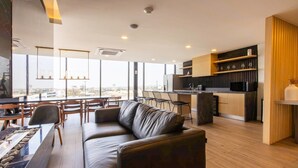 A modern interior with a leather sofa, dining area, and kitchen. - Modern Studio in Zona Rio with Panoramic View / Eazy stay / Tijuana (tijana)