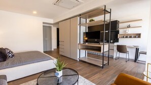 A modern apartment with a sofa, a round glass coffee table, a bed, a TV, and a kitchenette. - Modern Studio in Zona Rio with Panoramic View / Eazy stay / Tijuana (tijana)