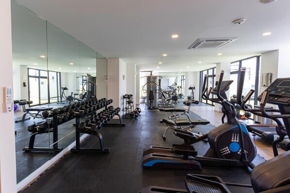 A gym with various exercise equipment, including treadmills, stationary bikes, and weight machines.