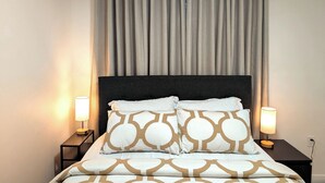 A neatly made bed with patterned pillows, a dark headboard, and two bedside lamps on matching nightstands. - Luxury Guest Suite in Calgary perfect for a visit to the Canadian Rockies. (Calgary)