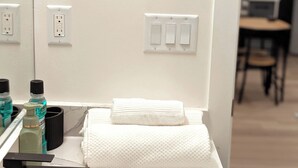 A bathroom with a white sink, a mirror, and a towel rack. There are toiletries on the counter and a chair in the background. - Luxury Guest Suite in Calgary perfect for a visit to the Canadian Rockies. (Calgary)
