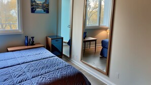 Ein Schlafzimmer mit einem Bett, einem Schreibtisch, einem Stuhl, einem Spiegel und einem Gemälde.