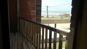 A wooden balcony with a railing overlooking a beach and a parking area. - Apart A Orillas del Mar (Costa Azul)