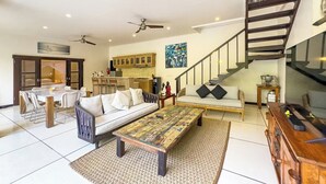 Amplia sala de estar con sofá, mesa de centro, mesa de comedor y una escalera que conduce a un nivel superior.