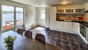 A modern kitchen with white cabinets, a dark tiled floor, and a view of a body of water through large windows. - 2 bedroom stunning home in Lepsøy (Lepsøy)