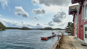 A wooden dock extending into a lake with a red building on the right. - 2 bedroom stunning home in Lepsøy (Lepsøy)