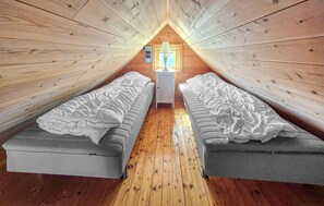 Une petite chambre mansardée avec deux lits simples, une petite table et une fenêtre donnant sur un paysage agréable.