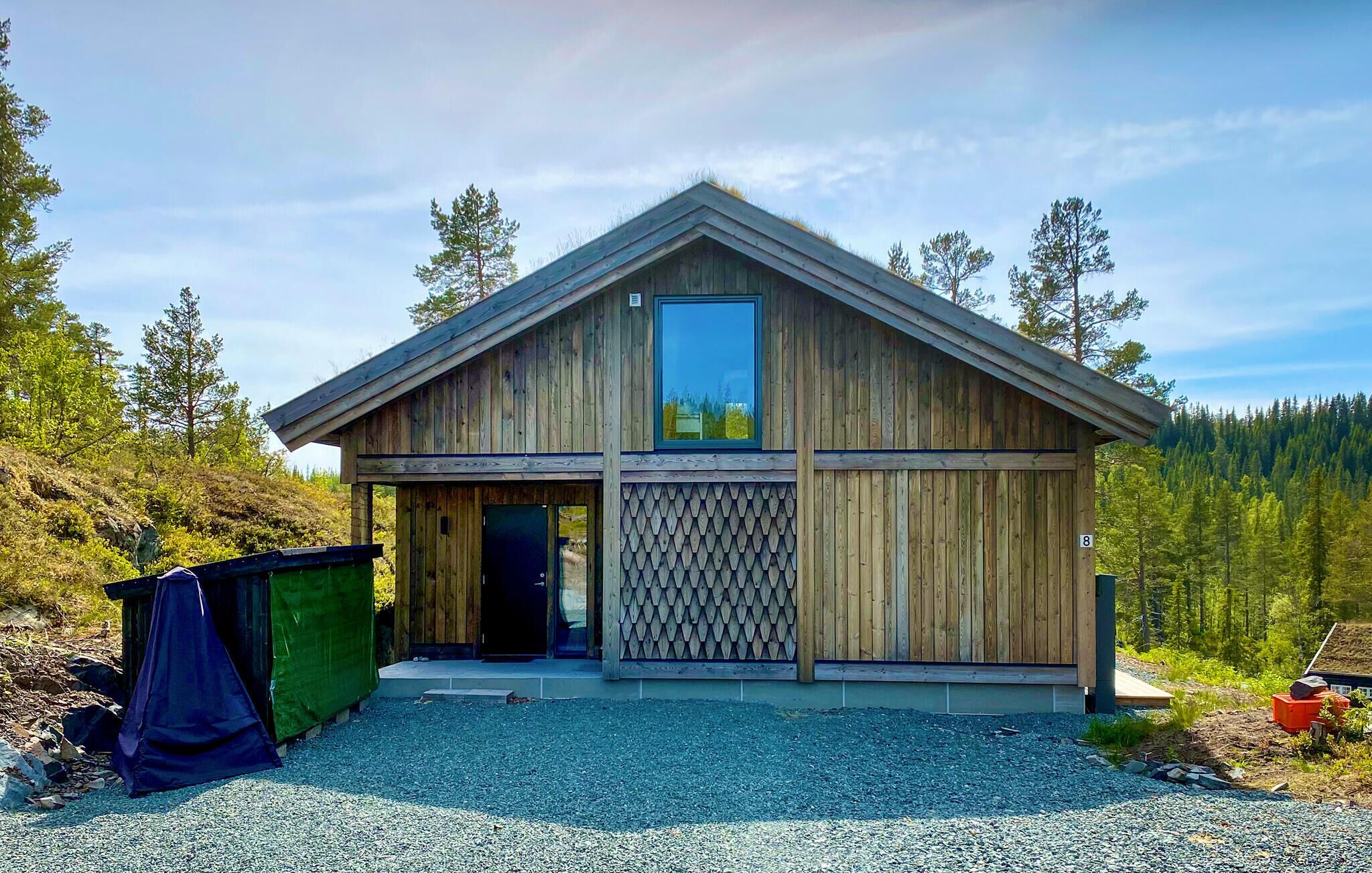 A wooden cabin with a large window, a door, and a lattice wall.