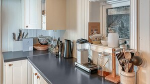 Een keuken met een zwart aanrecht, diverse keukenapparaten en keukengerei.