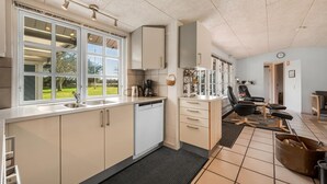 A modern kitchen with a dishwasher, a coffee maker, and a large window offering a view of the outdoors. - Gorgeous home in Tarm with WiFi (Tarm)