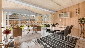 A modern dining area with a round table and chairs, large windows, and a wooden wall. - Gorgeous home in Tarm with WiFi (Tarm)
