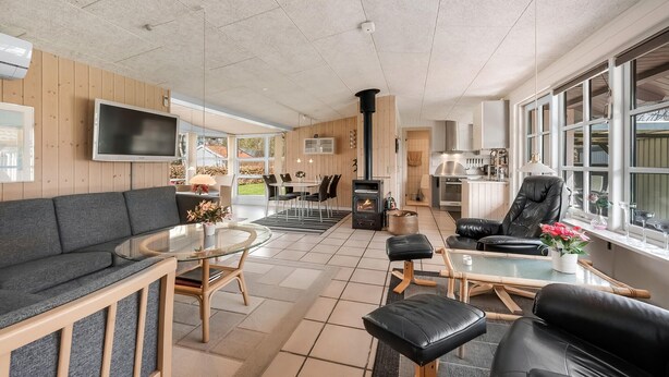 A spacious living area with a sofa, a glass coffee table, a fireplace, and a dining area with chairs and a table. - Gorgeous home in Tarm with WiFi (Tarm)