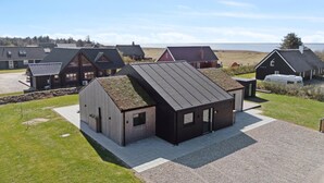 A modern building with a sloped roof, a gravel driveway, and a view of the sea. - 5 bedroom gorgeous home in Skjern (Skjern)