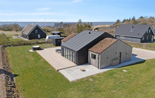 Une maison moderne dotée d’une grande terrasse, d’un jacuzzi et offrant une vue sur la mer.