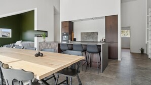 A modern kitchen with a central island, dark wood cabinets, and a large dining table with chairs. - 5 bedroom gorgeous home in Skjern (Skjern)
