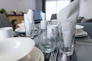 Mesa posta com pratos brancos, copos e guardanapos.