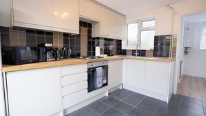 A modern kitchen with white cabinets, black and beige tiles, a microwave, coffee maker, and a dishwasher. - 3-bed House - Sleeps 7, Parking & Views (Belvedere)