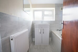 Casa de banho com armário branco, lavatório e banheira.