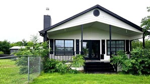 A single-story house with a white exterior, black trim, and a covered porch.