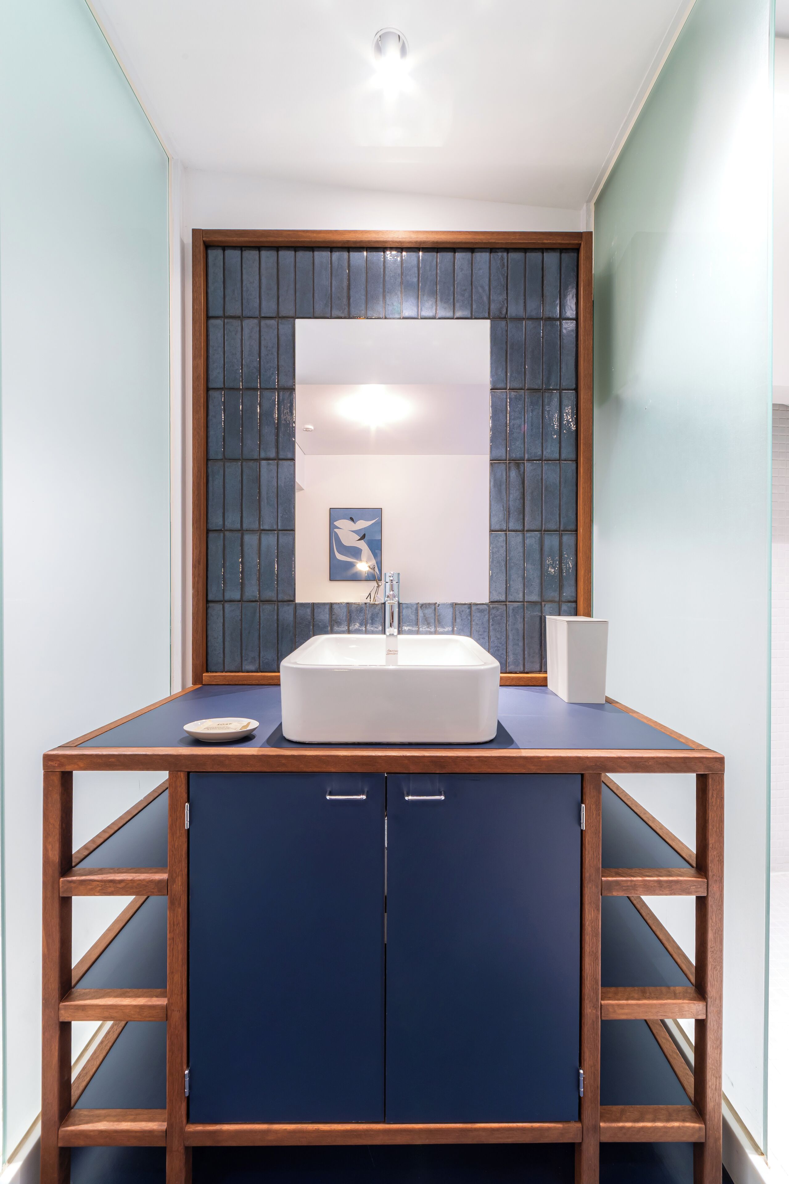 A bathroom with a white sink, a mirror, and a blue cabinet.