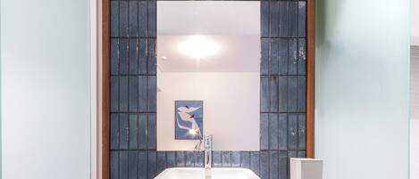 A bathroom with a white sink, a mirror, and a blue cabinet.
