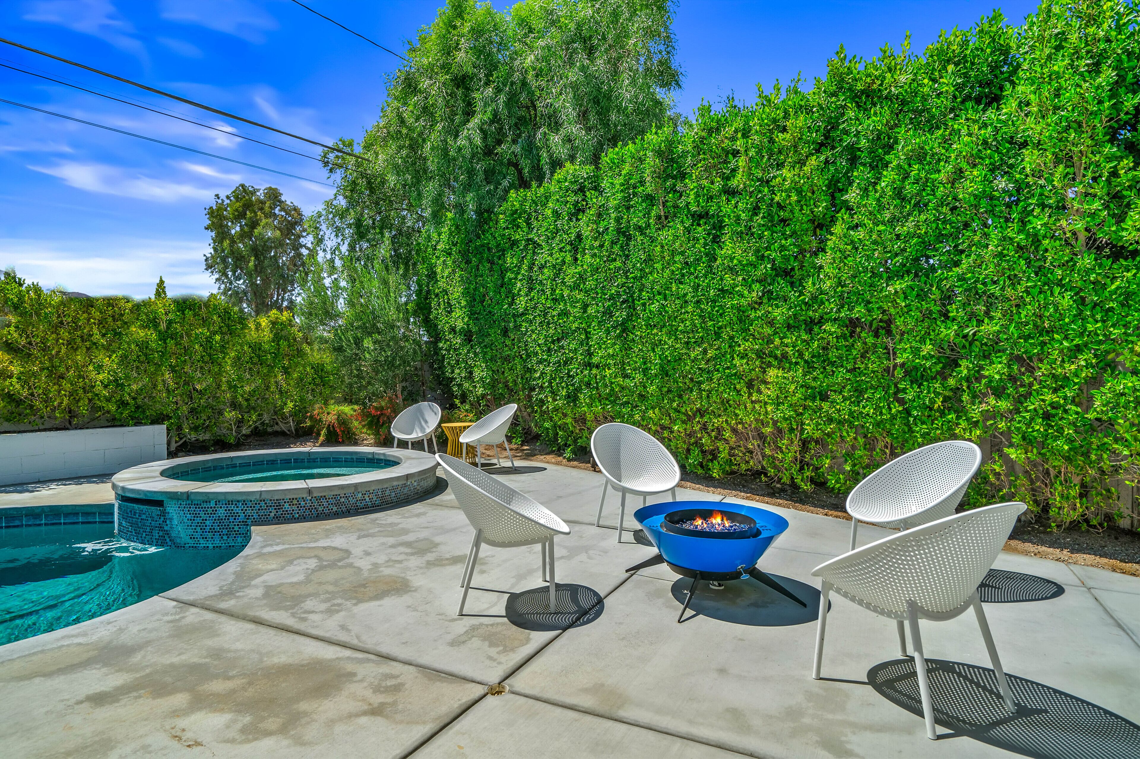 Un jardin avec une piscine, un jacuzzi et un espace salon extérieur.