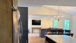 Una cucina moderna con un'isola grande, pavimento in legno e una TV a schermo piatto montata a parete.