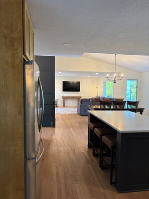 Una cocina moderna con una isla grande, suelo de madera y un televisor de pantalla plana montado en la pared.