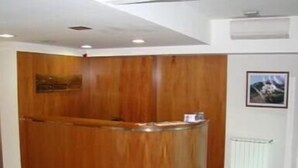 Ένας πάγκος υποδοχής με επένδυση από ξύλο, ένα λευκό ταβάνι και μια κορνιζαρισμένη εικόνα στον τοίχο.