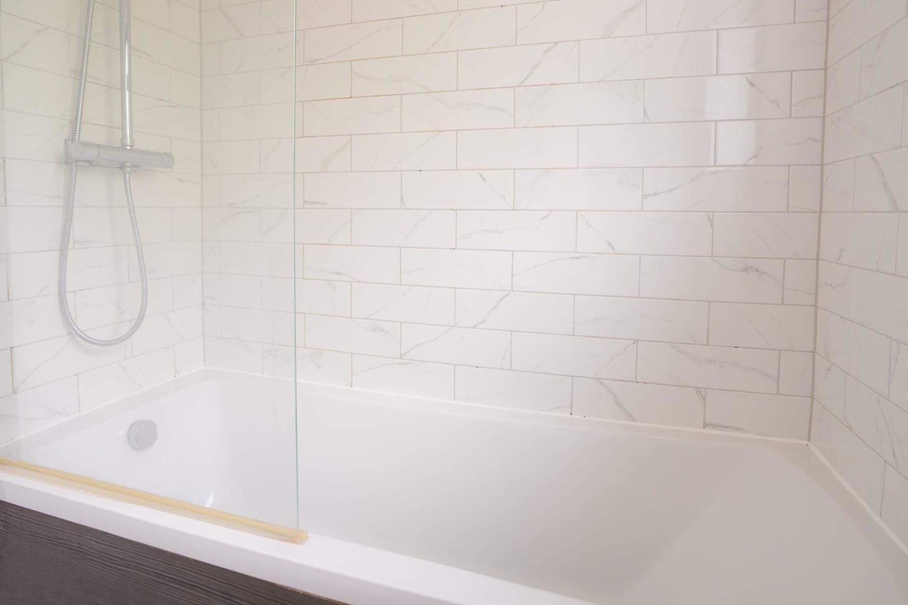 Une cabine de douche dotée d’une porte en verre et d’un pommeau de douche.