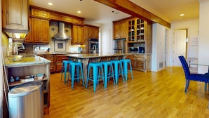 A spacious kitchen with wooden cabinets, a central island with bar stools, and a stainless steel sink.