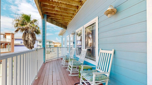 A wooden deck with rocking chairs and a hanging plant.