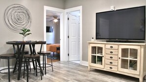 Ein Wohnzimmer mit Essbereich, Fernseher und Schrank.