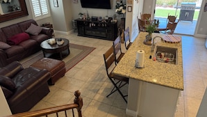 A modern living room with a brown leather sofa, a coffee table, and a TV mounted on the wall. - Sweet home with electric car charger 
 unwind, relax enjoy a great time in Vegas (Henderson)