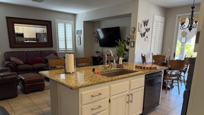 A spacious kitchen with a granite countertop, white cabinetry, and a built-in dishwasher. - Sweet home with electric car charger 
 unwind, relax enjoy a great time in Vegas (Henderson)