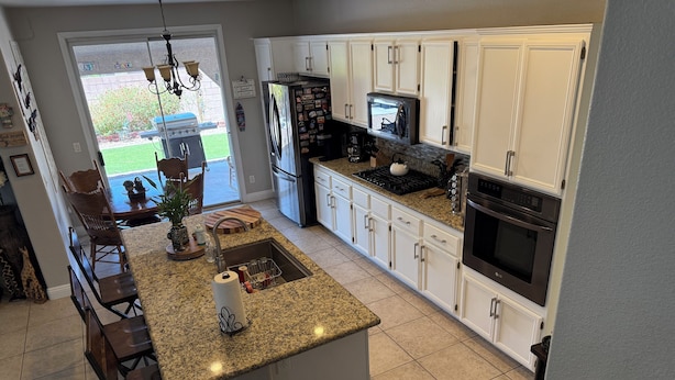 A modern kitchen with white cabinets, granite countertops, a central island, and stainless steel appliances. - Sweet home with electric car charger 
 unwind, relax enjoy a great time in Vegas (Henderson)