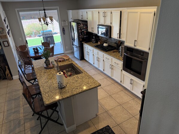 A modern kitchen with white cabinets, granite countertops, a central island, and stainless steel appliances. - Sweet home with electric car charger
unwind, relax enjoy a great time in Vegas (Henderson)