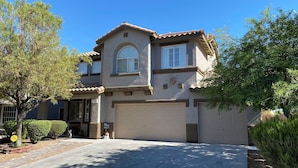 A two-story house with a garage, a sunburst design on the facade, and a clear blue sky. - Sweet home with electric car charger 
 unwind, relax enjoy a great time in Vegas (Henderson)