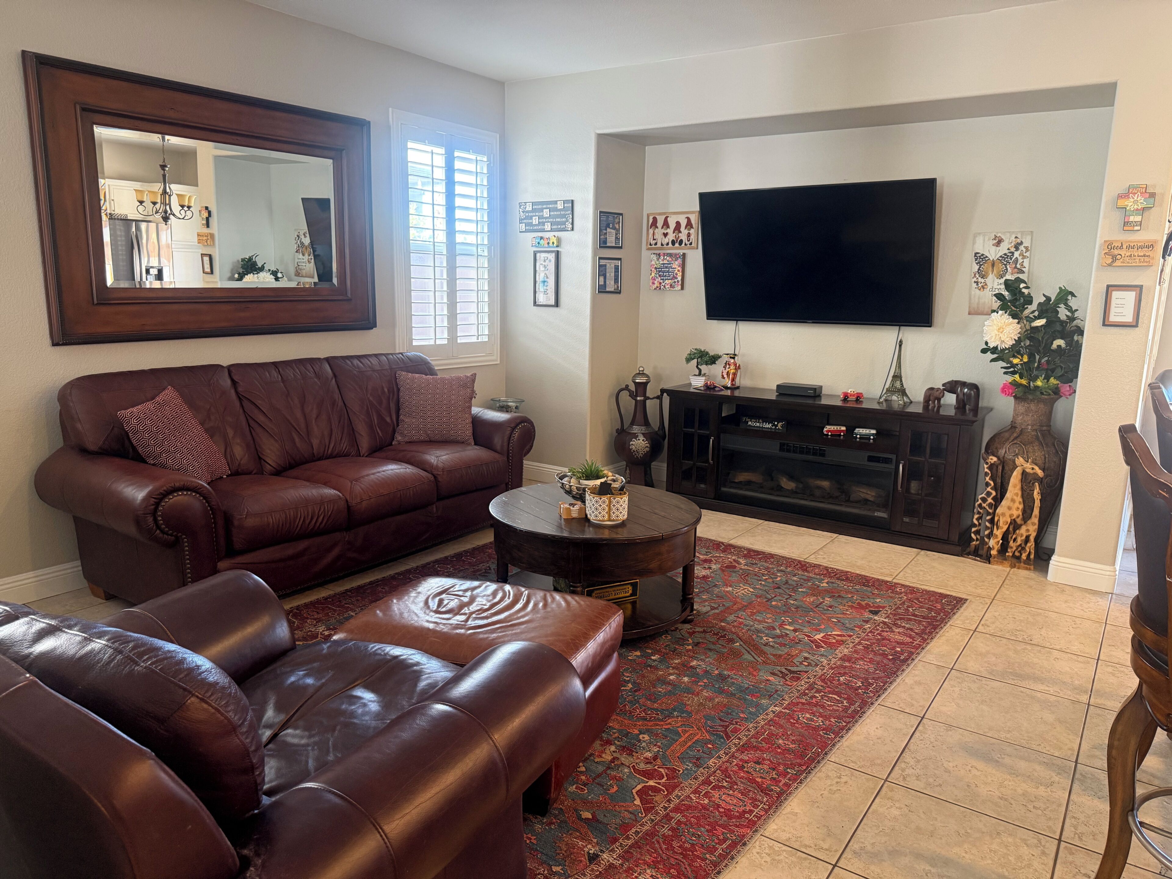 A living room with a brown leather sofa, a coffee table, a TV, and a fireplace.